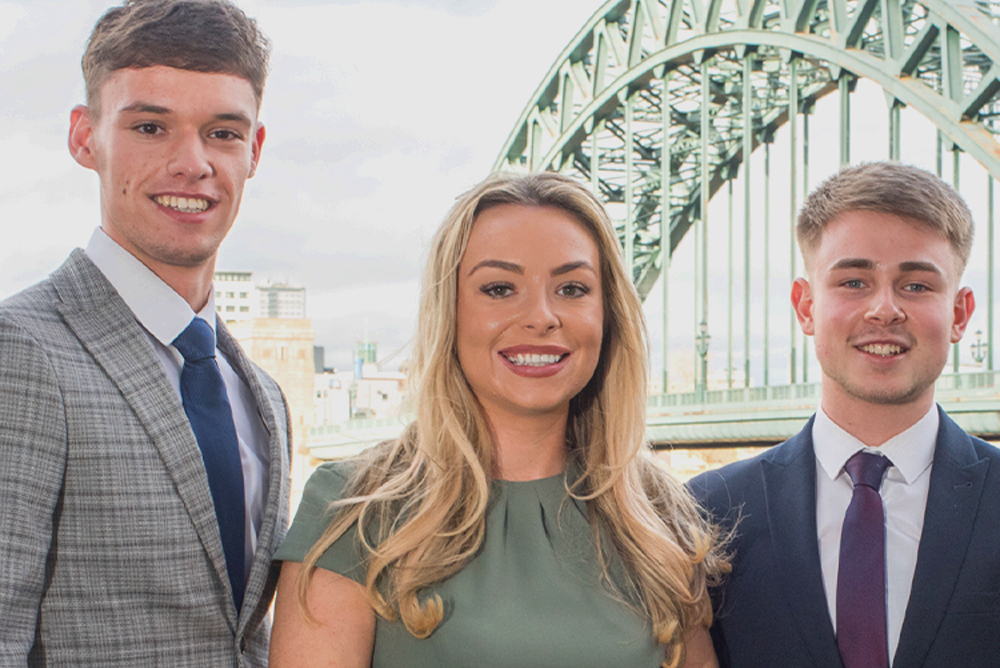 Three apprentices from Fairstone stand in front of Newcastle's Tyne Bridge