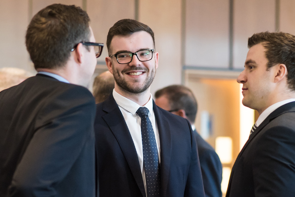 Three Fairstone staff face each other wearing suits whilst having a conversation